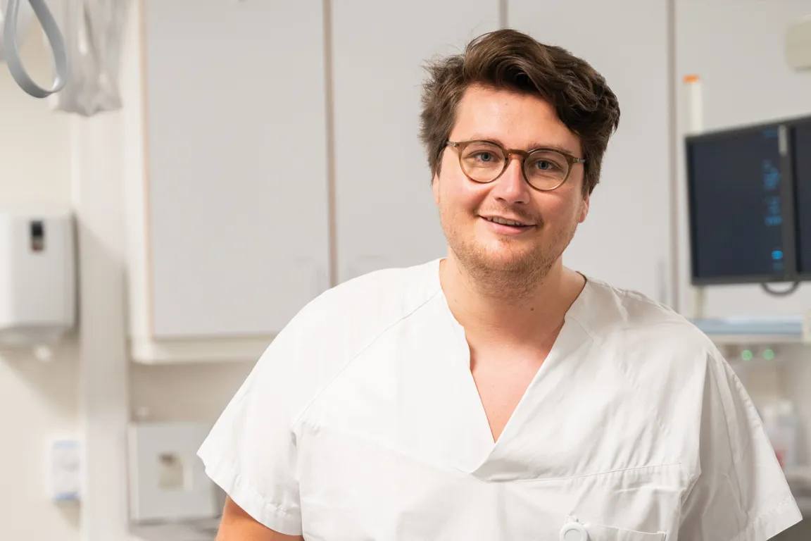 Lis-lege kledd i hvit uniform smiler mot kamera.