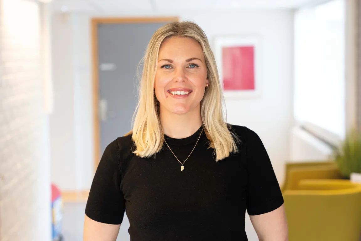 En psykologspesialist står smilende i en sykehuskorridor.