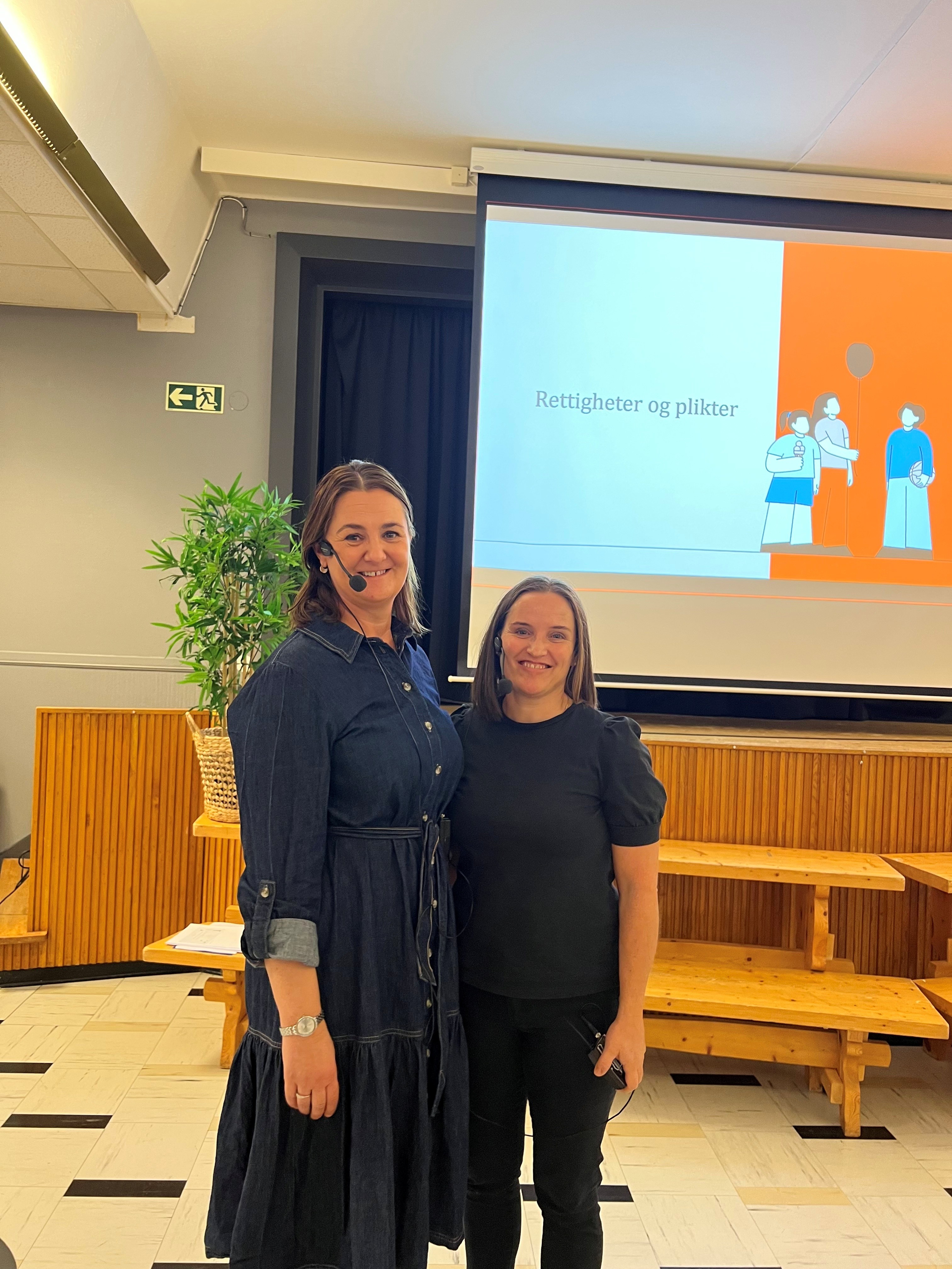 Et par kvinner som poserer for et bilde foran en stor skjerm