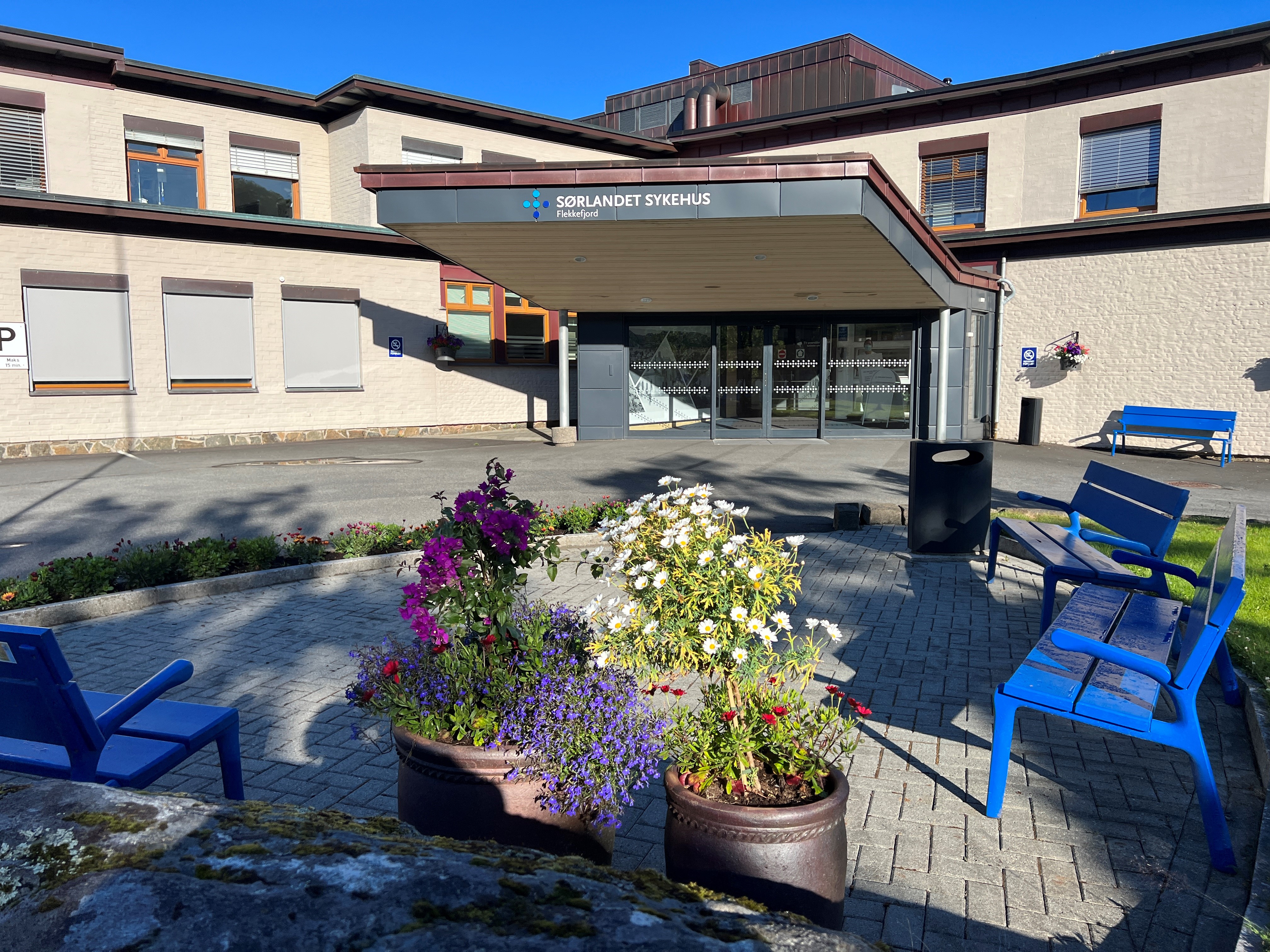 Hovedinngang til Flekkefjord sykehus med uteplass med stoler og blomster